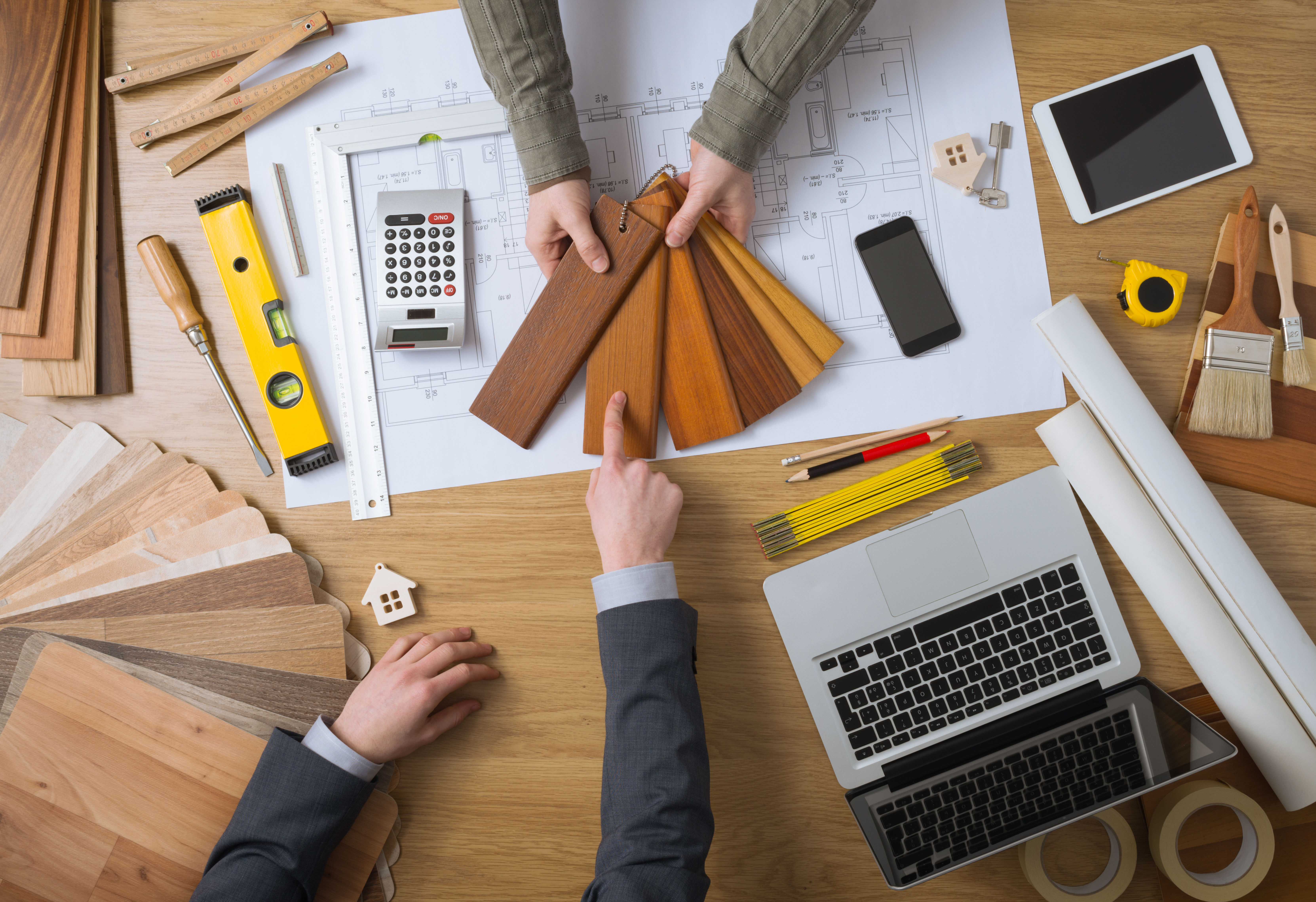 Interior designer showing wood swatches to his customer, laptop, tools and house projects on desktop top view